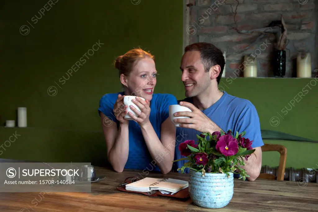 A couple sitting at a dining table with a personal organizer, talking over coffee