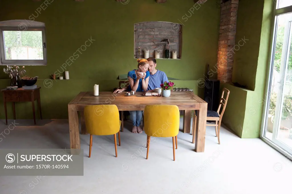 An affectionate couple sitting at a table with a personal organizer and coffee