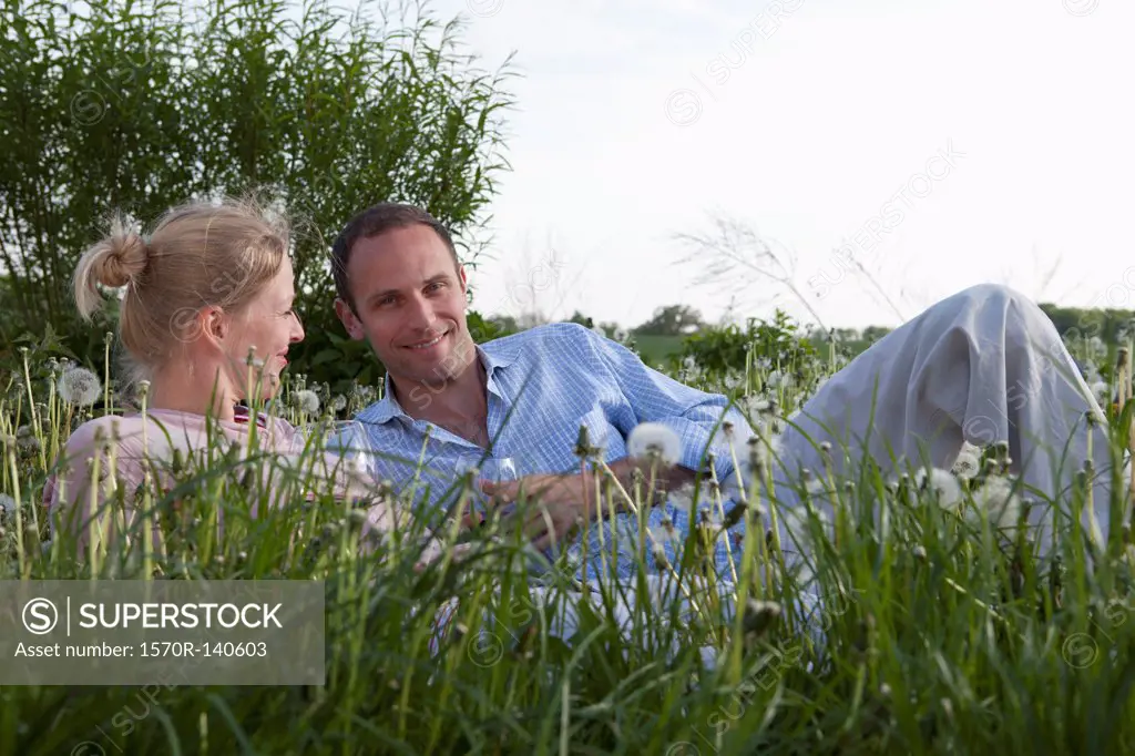 A couple lying in the grass enjoying some red wine