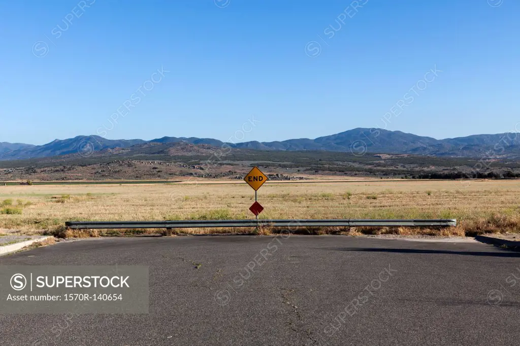 An END road sign and mountain ranges behind