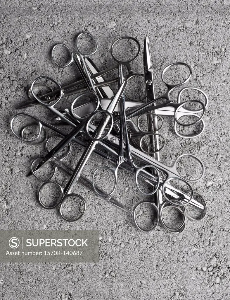 A pile of surgical scissors on cement