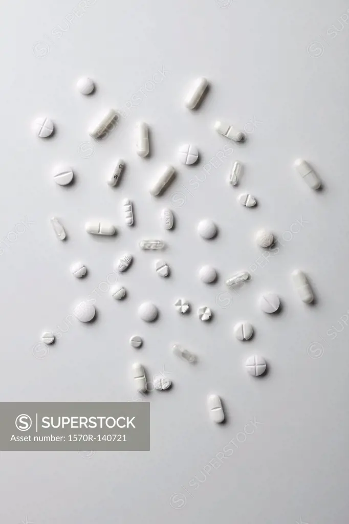 Various white pills and capsules spread out on a white surface