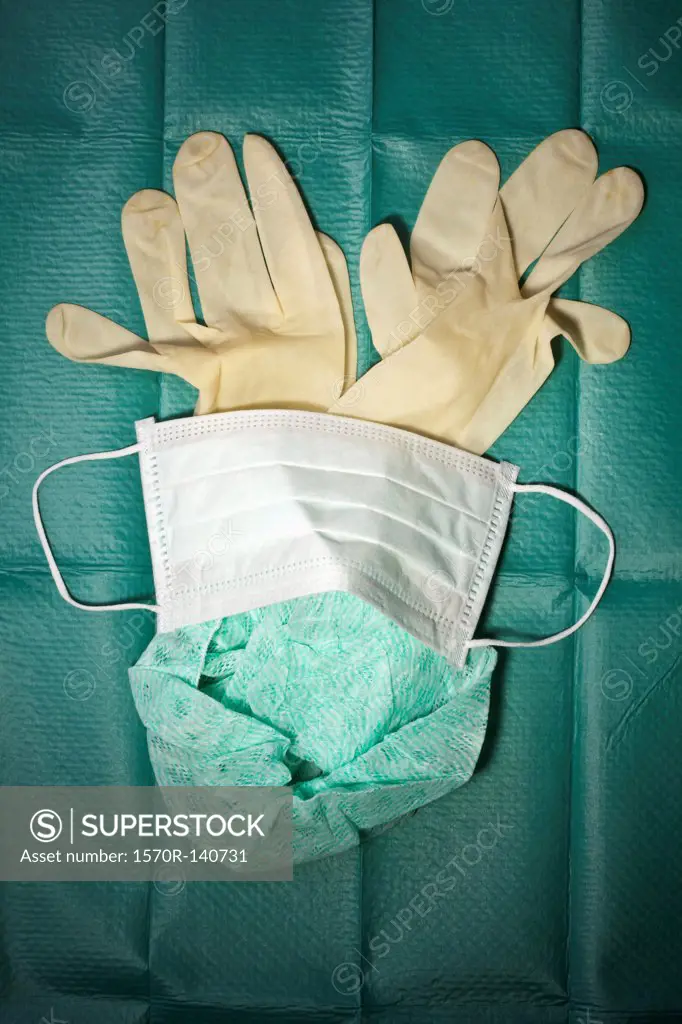 Surgical mask, cap and gloves arranged on a surgical drape