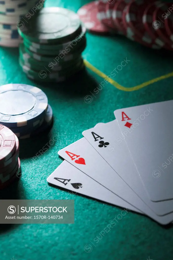 A hand of cards displaying four aces, gambling chips in background