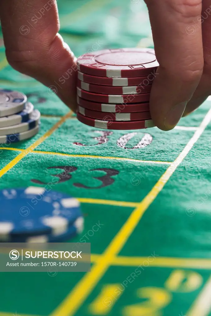 A man placing gambling chips on number 30, detail of fingers