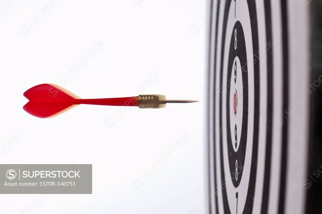 Side view of a dart flying towards the bull's eye of a target