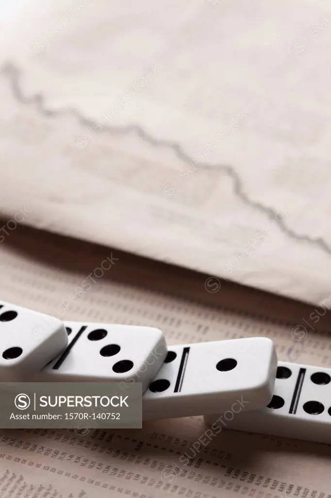 Fallen dominoes on a financial newspaper page