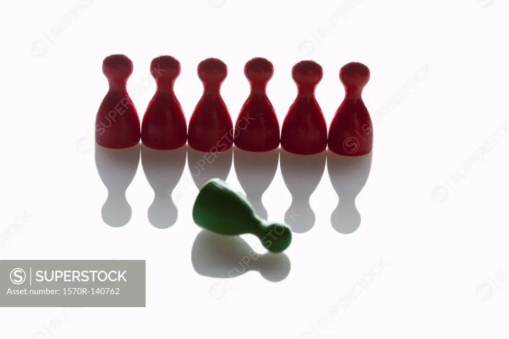 A row of red game pieces with a green piece knocked over in front of them