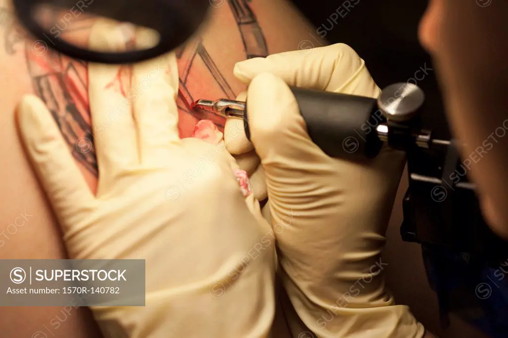 Close-up of a tattoo artist tattooing a design on human skin