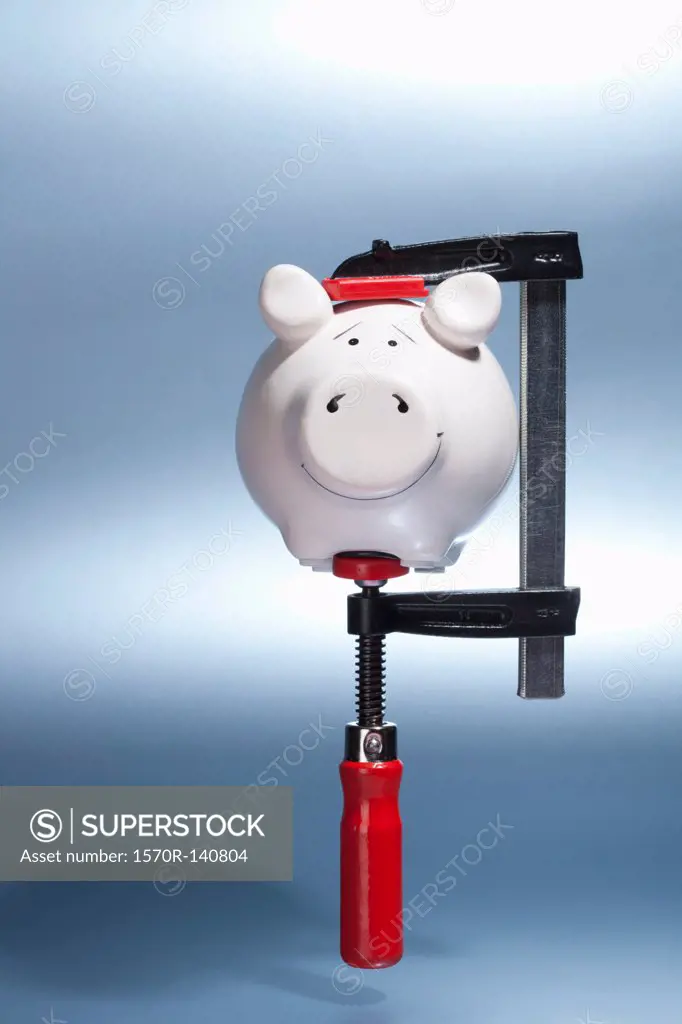 A piggy bank being held in a vise grip suspended in mid-air