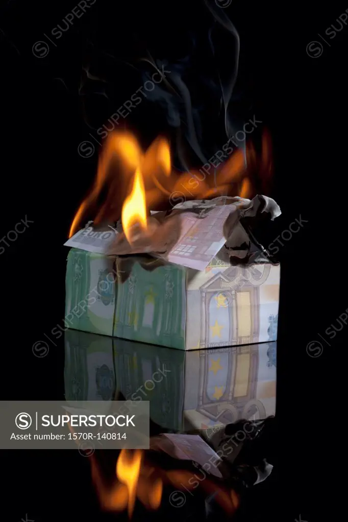 European Union currency folded into a house and on fire