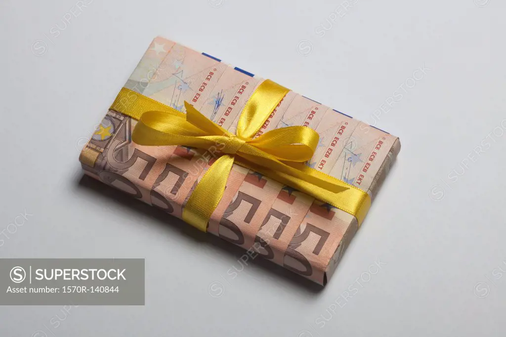 Fifty Euro banknotes used to wrap a gift with a yellow bow