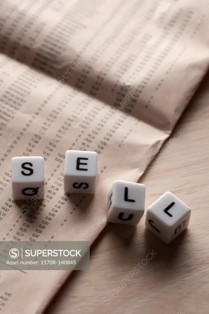 Lettered cubes spelling SELL lying on top of a financial page