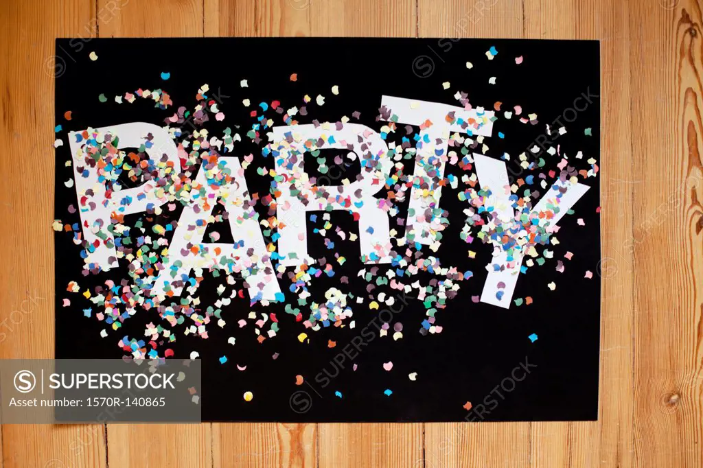 Confetti and letters spelling PARTY on a black poster board