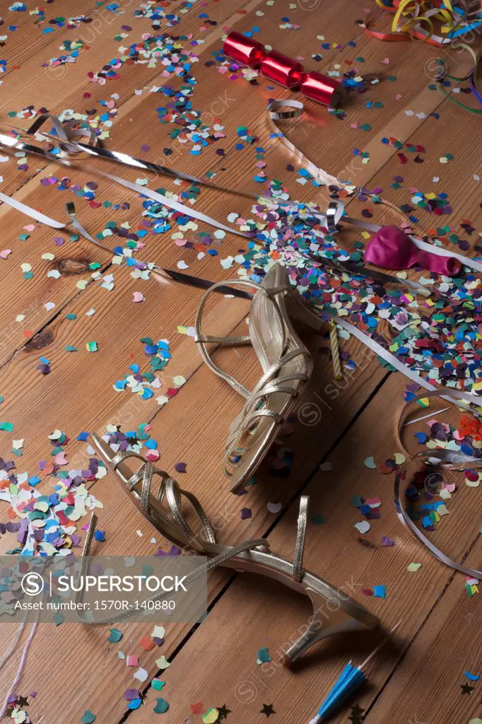 Metallic strappy heels, confetti and streamers littering a hardwood floor