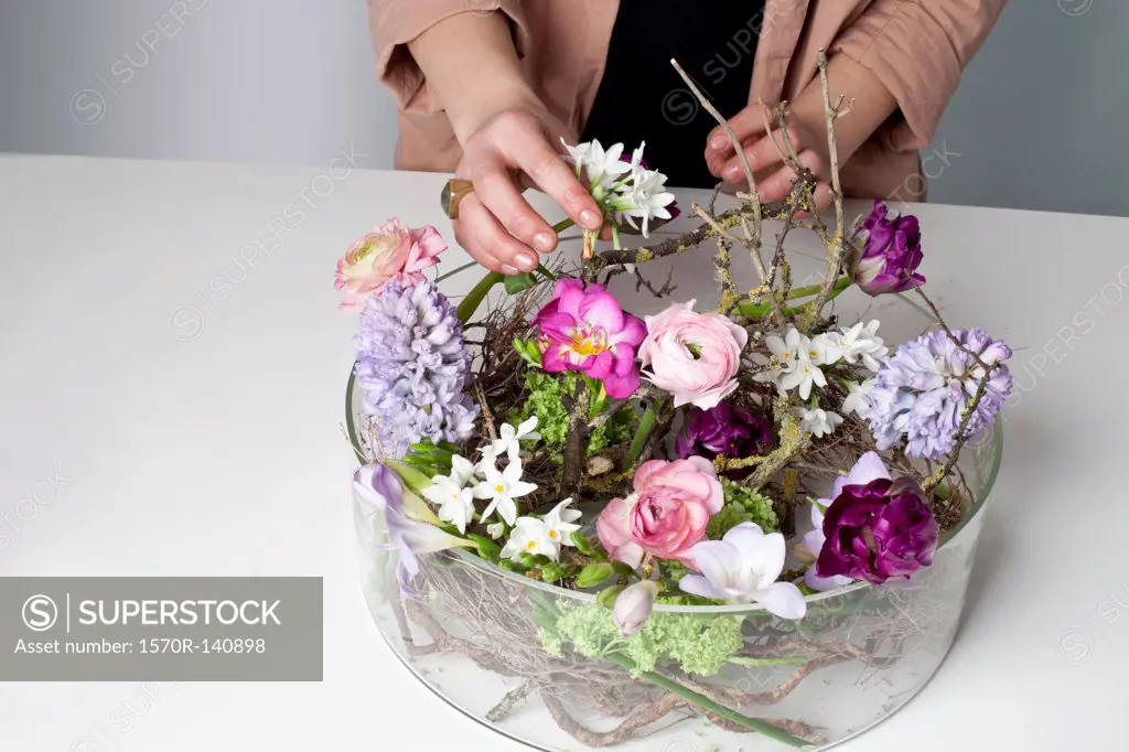 A florist arranging flowers in a glass bowel vase