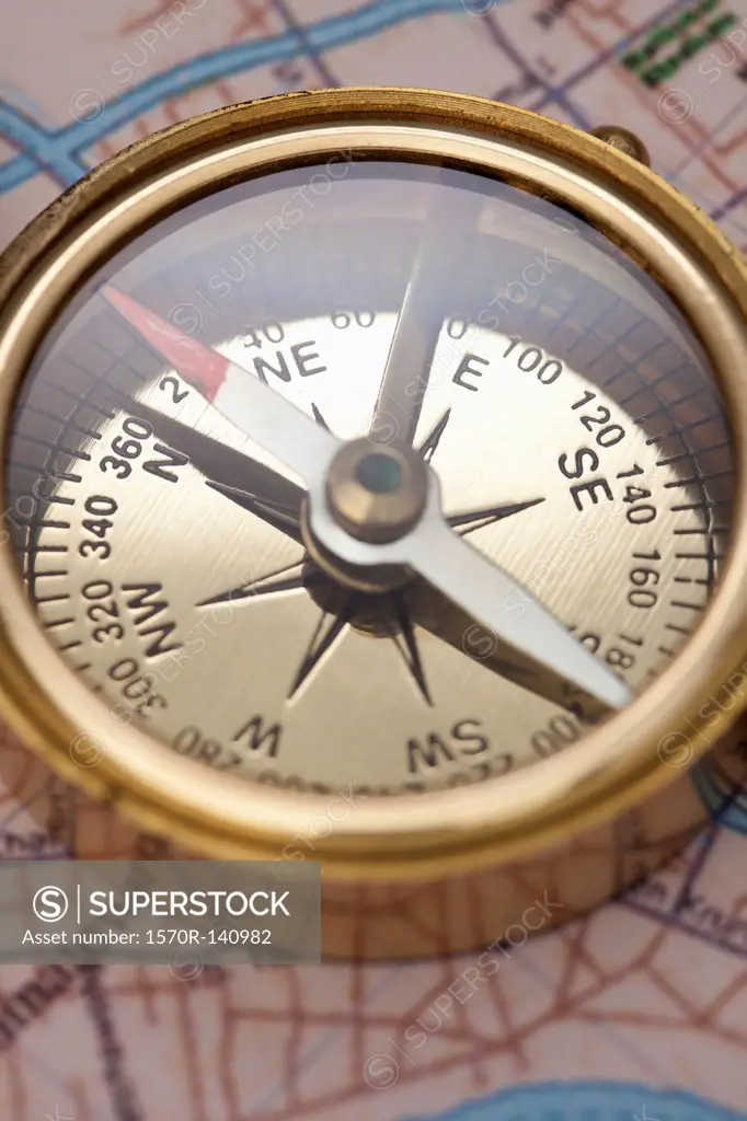 A compass on top of a road map, focus on compass