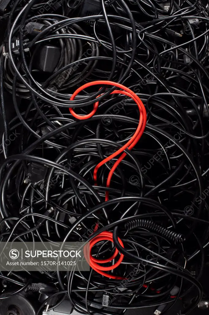 A single red cord in the form of a question mark amongst a tangle of black cords and cables