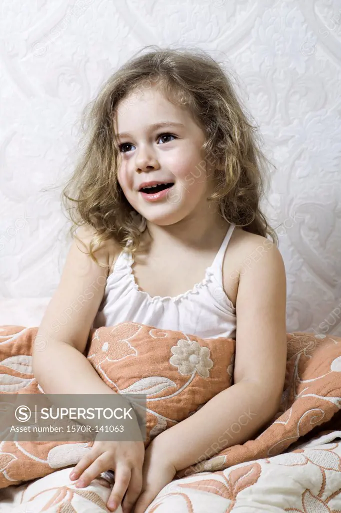 A young girl sitting under a blanket