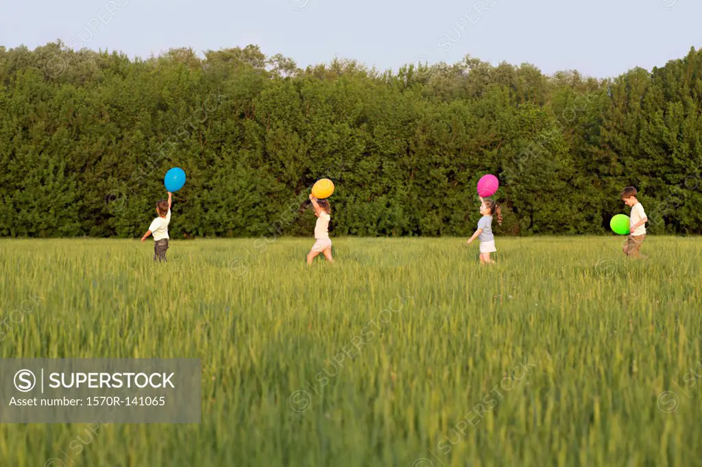 Children walking in a field with balloons