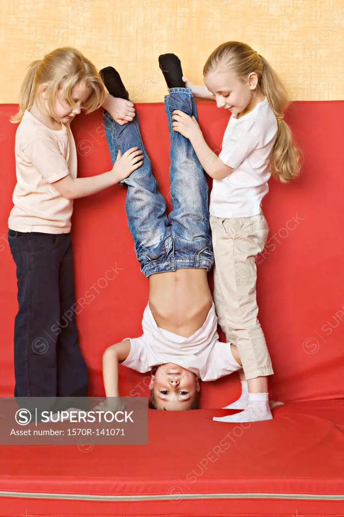 Two girls holding a boy upside down