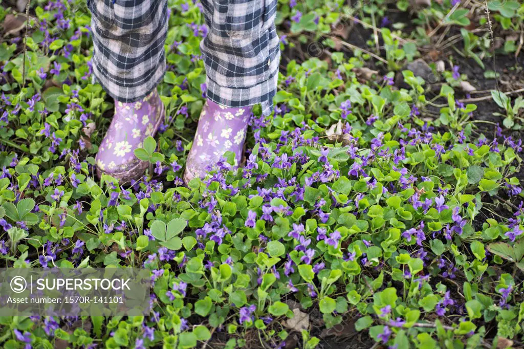 Low section of a girl standing in a garden with gumboots
