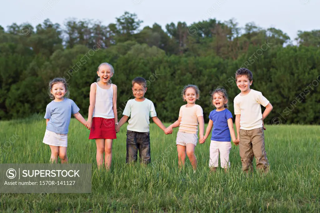 Children holding hands and standing in a field