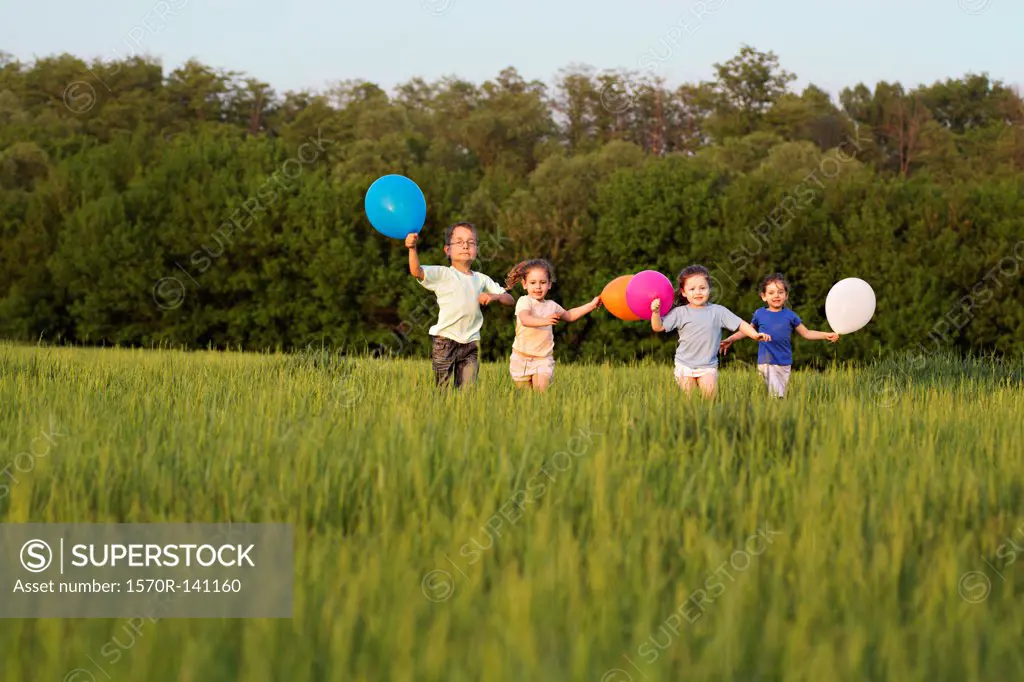 Children running in a field with balloons