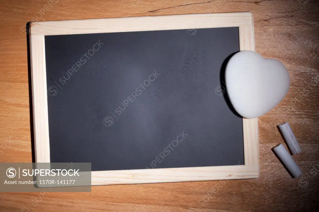 A small blank chalkboard with chalk and a heart shaped eraser