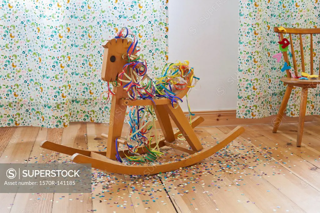 A rocking horse amongst streamers, confetti and happy birthday banner