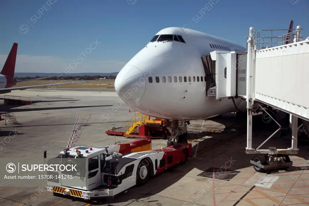 Jumbo jet attached to boarding bridge with tug in front