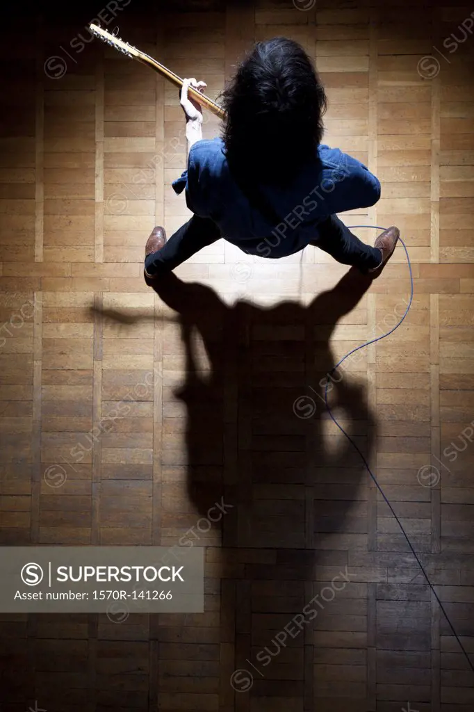 Guitarist in spotlight creating a shadow symbol of the 'sign of the horns'
