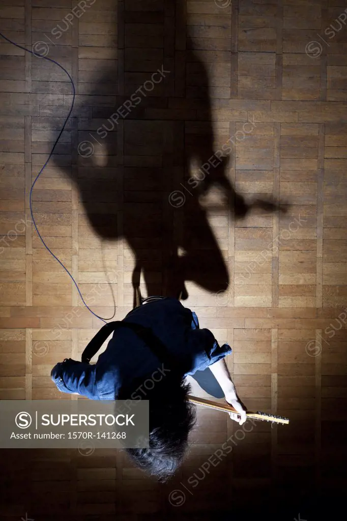 Guitarist sitting on stage in spotlight