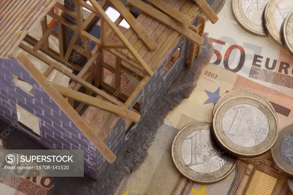 A partially constructed miniature model of a house standing on top of European Union currency