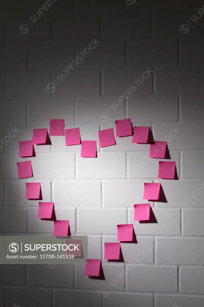 Blank adhesive notes arranged into the shape of a heart on a brick wall