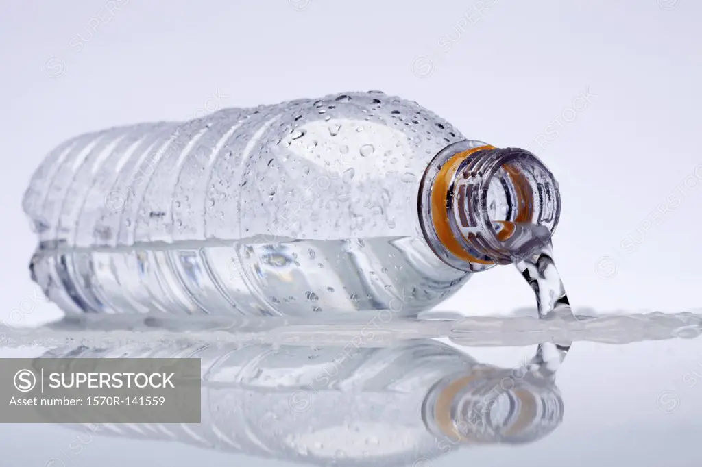 A plastic water bottle lying on its side, water spilling out