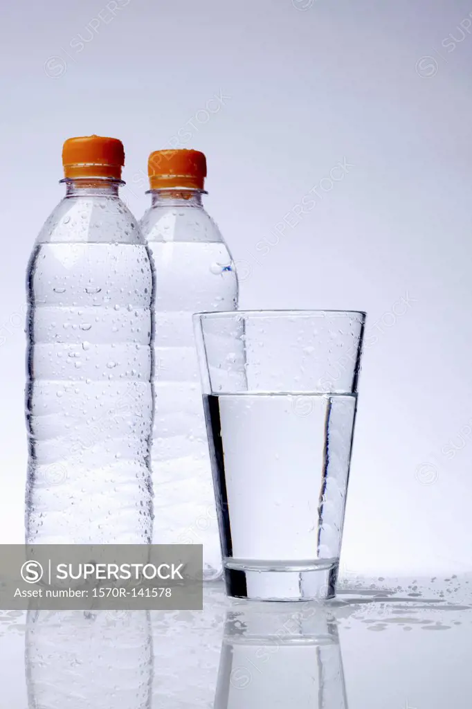 Two full plastic water bottles and a drinking glass