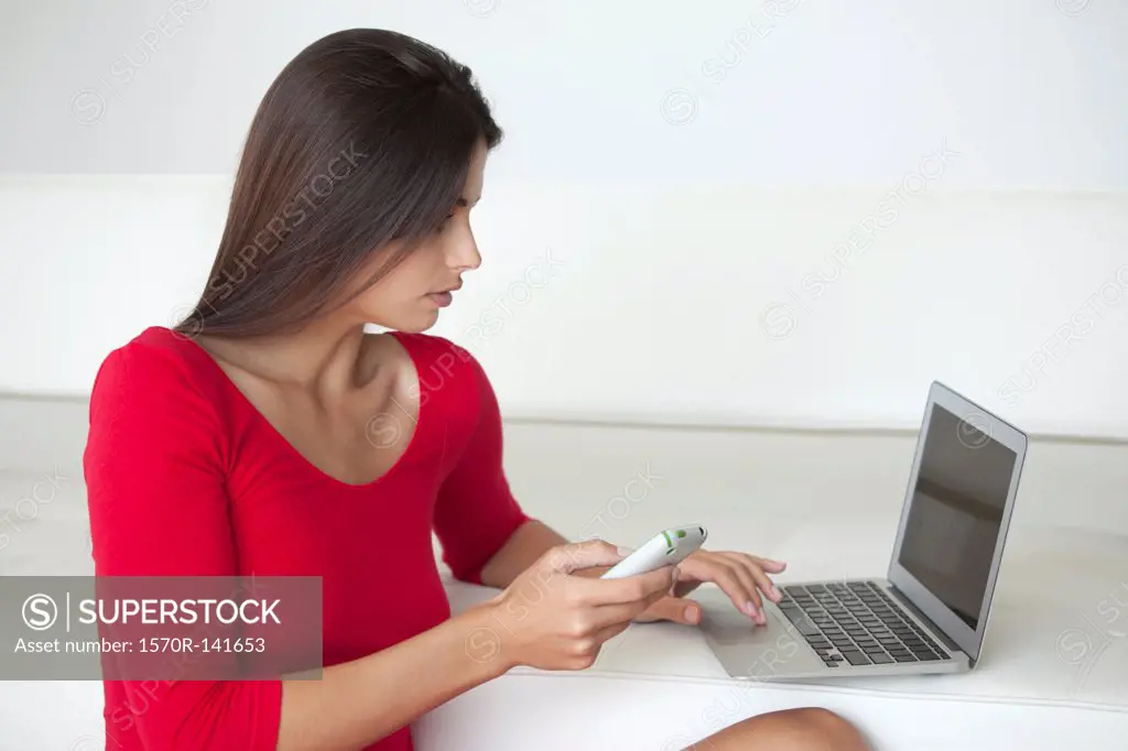 Woman in red using phone and laptop