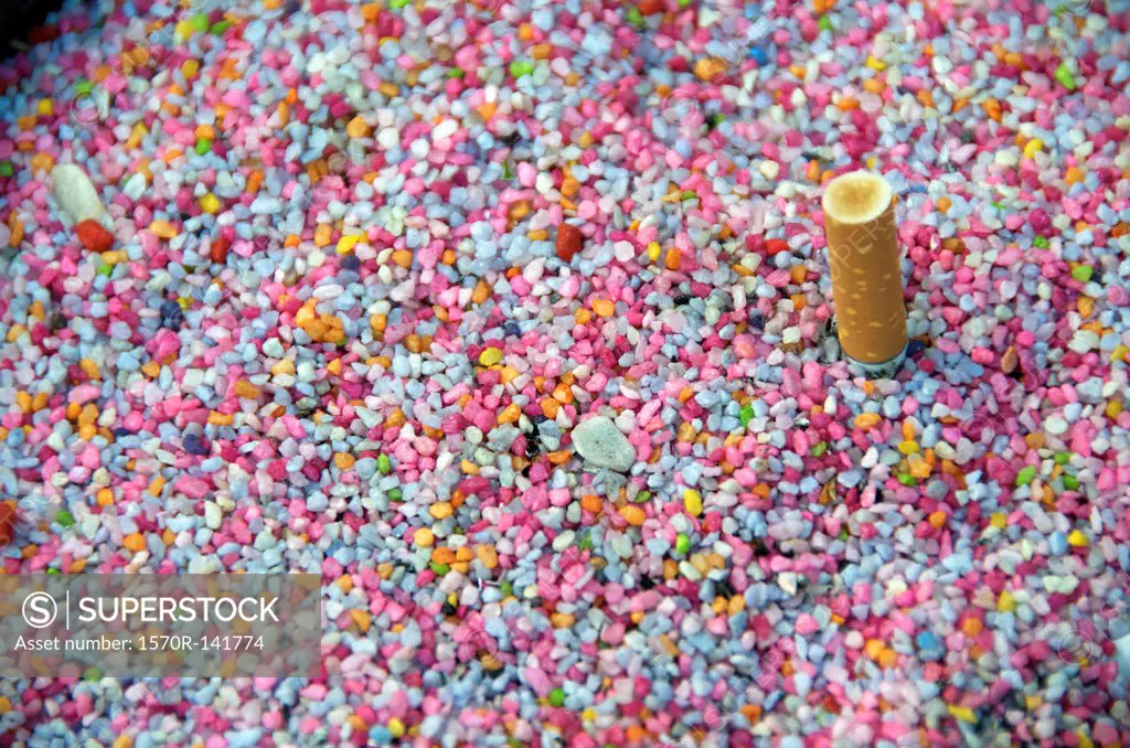 Cigarette stubbed out in multi colored pebbles