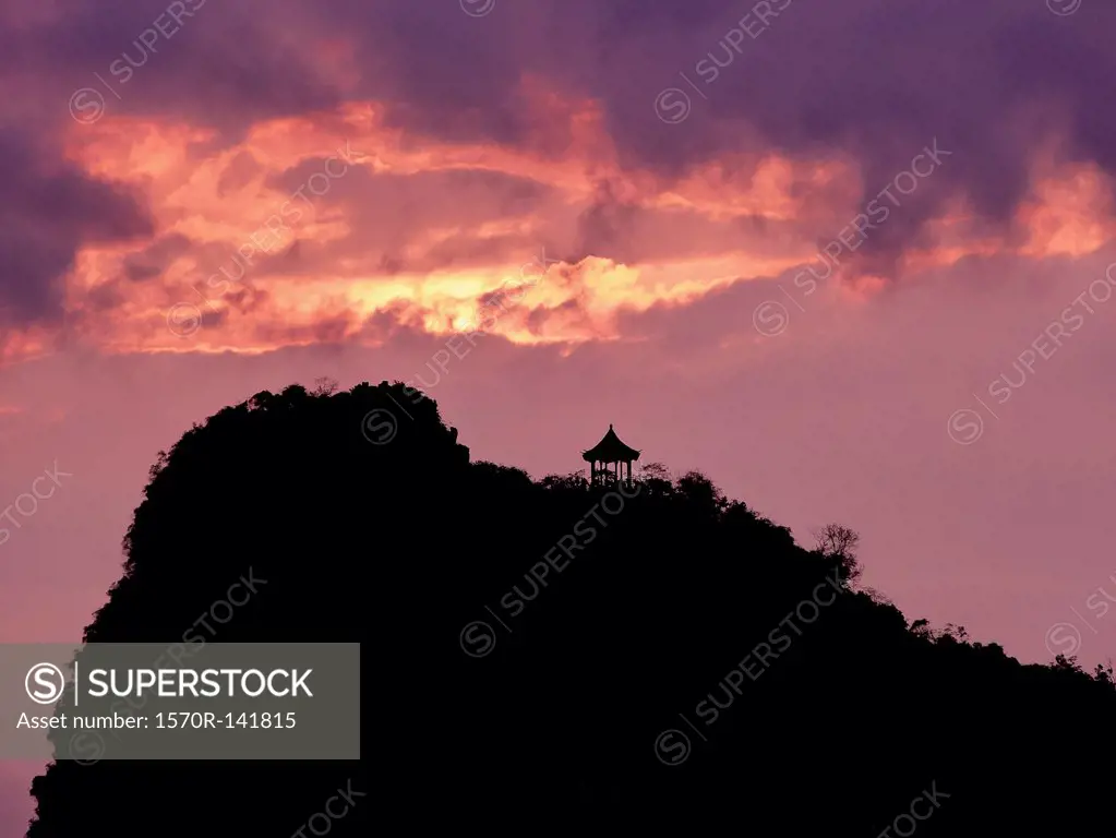 A pagoda on a hill in silhouette against a dramatic sky, Guilin River, Guilin, China