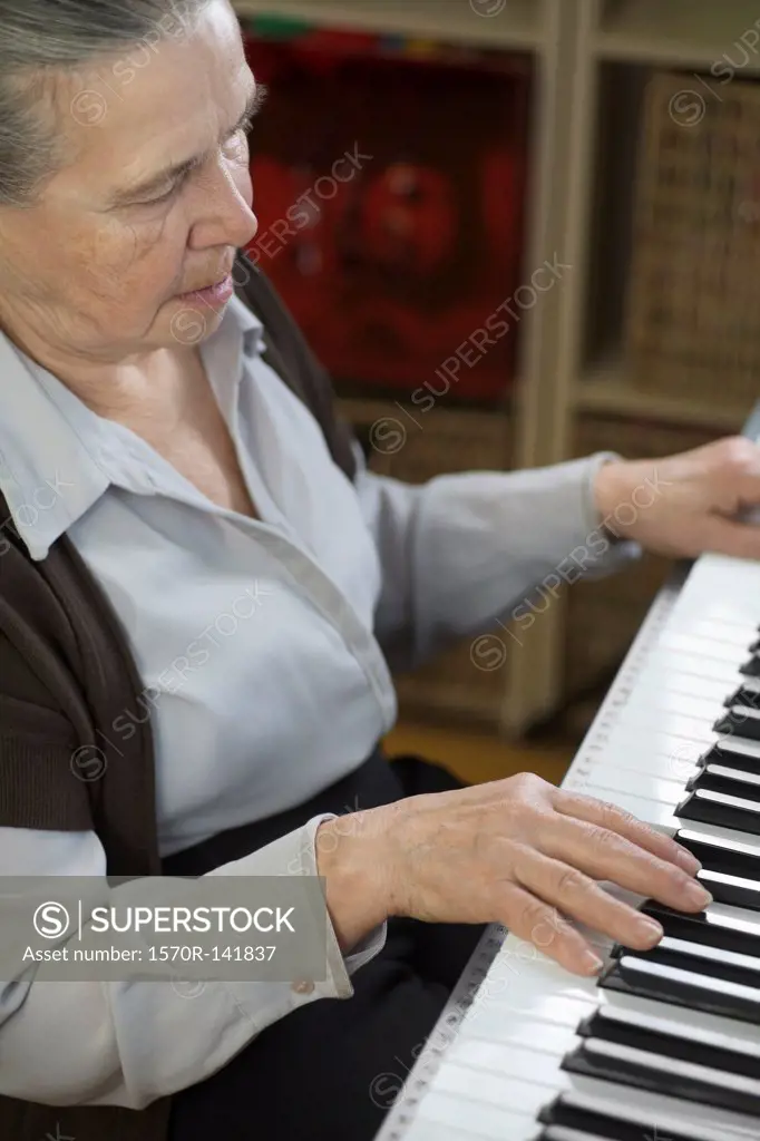 A senior woman playing an upright piano