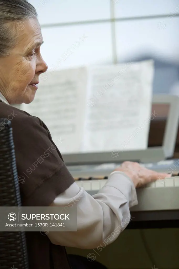 A senior woman sitting at piano