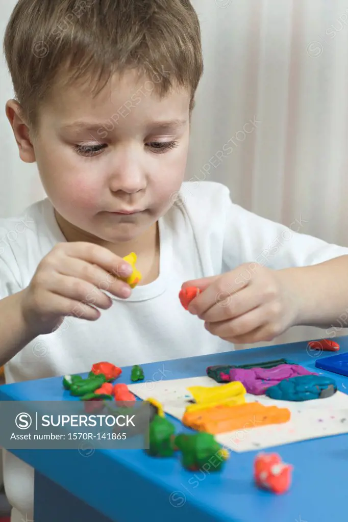 A young boy playing with various colored child's play clay