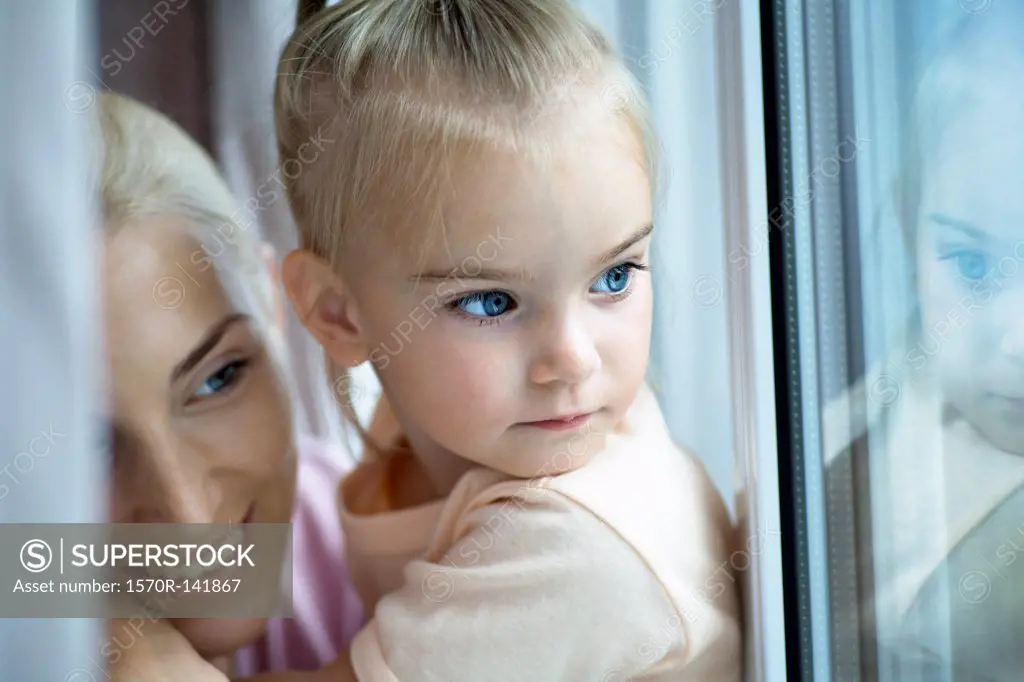 A mother and daughter looking out a window