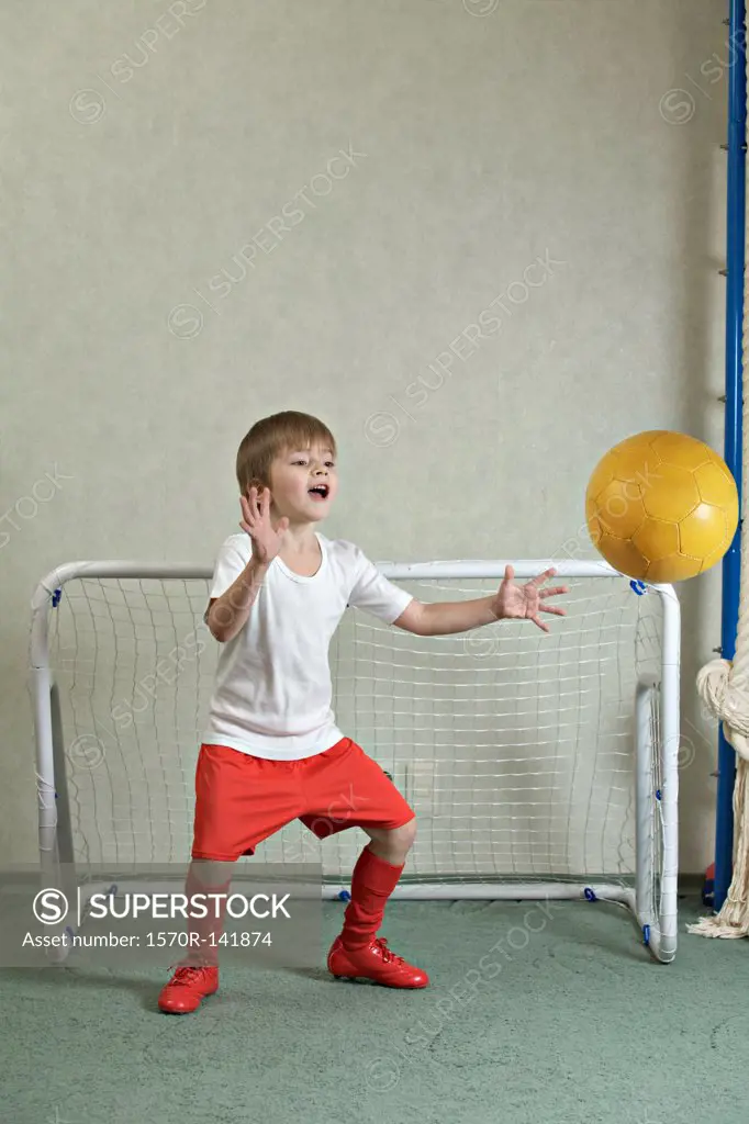 A young boy defending a goal while a ball flies towards him