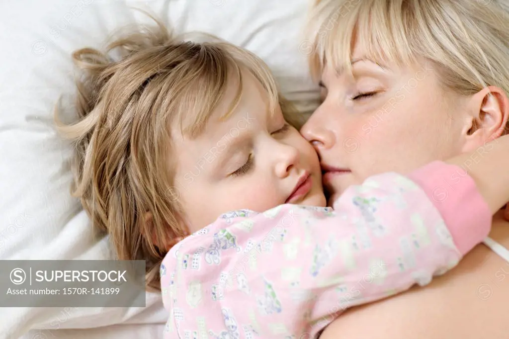 A mother and her young daughter sleeping a bed side by side