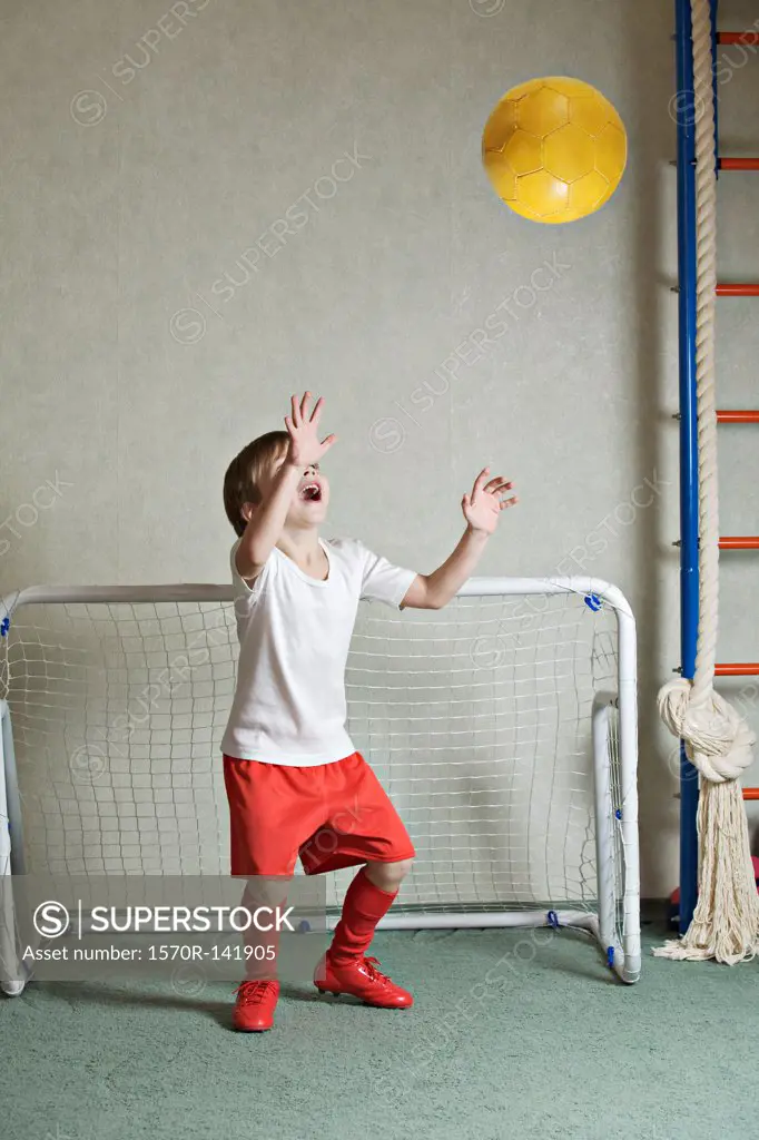 A young boy defending a goal while a ball flies towards him