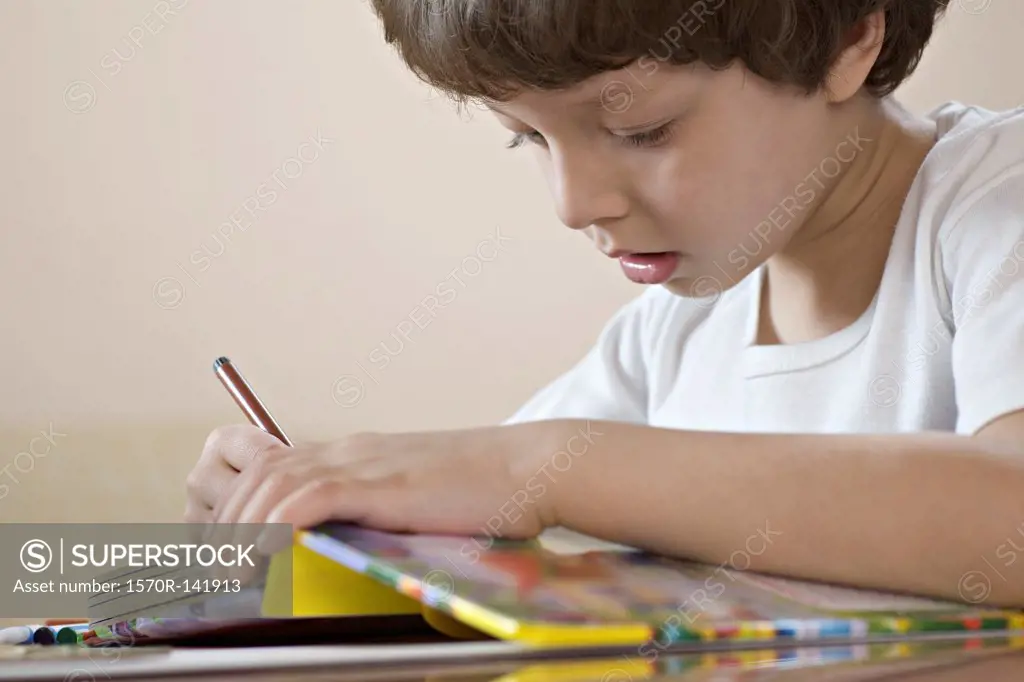A young boy concentrating on his workbook