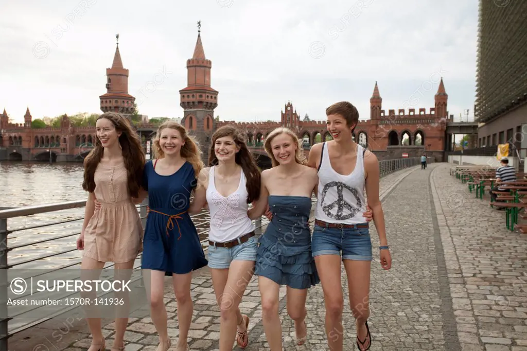 Five female friends walking side by side near the Oberbaumbruecke, Berlin, Germany