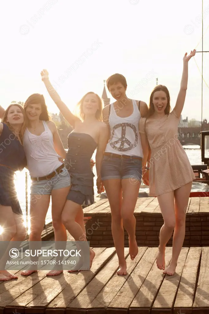 Five young female friends celebrating on a jetty, Spree River, Berlin, Germany